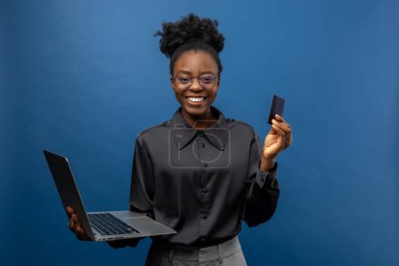 Foto de Mujer de negocios afroamericana con una tarjeta de crédito y un portátil en las manos - Imagen libre de derechos