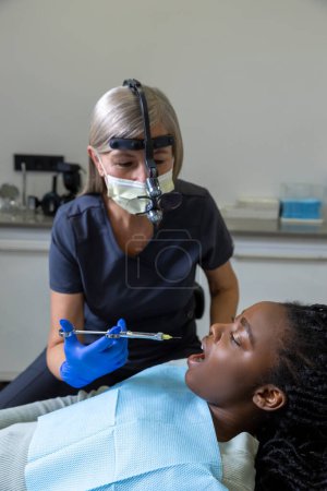 Photo for Dentist checking teeth of patient woman sitting in medical center professional oral care - Royalty Free Image