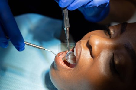 Zahnarzt überprüft Zähne einer multikulturellen Patientin in modernem medizinischen Zentrum