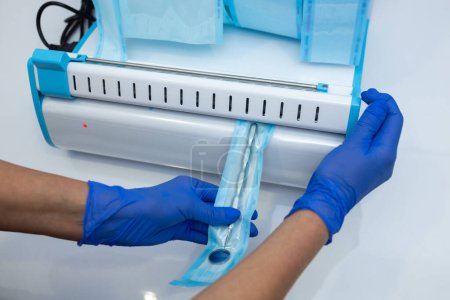 Téléchargez les photos : Médecin méconnaissable effectuant une procédure de stérilisation mains dans des gants bleus tenant des outils de dentiste - en image libre de droit