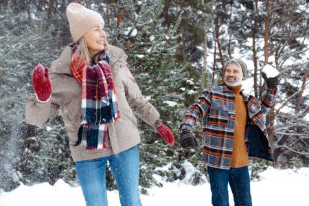 Photo for Playing snowballs. Happy couple playing snowballs and looking involved - Royalty Free Image