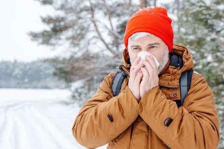 Téléchargez les photos : Je suis malade. L'homme dans une forêt d'hiver a l'air malade et a le nez qui coule - en image libre de droit