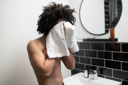 Photo for Hygiene. Young man in the bathroom drying off his face with the towel - Royalty Free Image