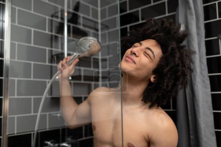 Photo for Shower. Young man having a shower and looking pleased and joyful - Royalty Free Image