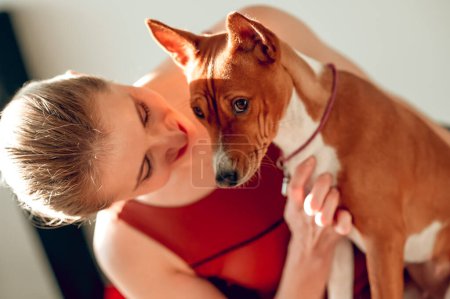 Téléchargez les photos : Belle femme sportive tenant un chien dans un studio de fitness - en image libre de droit