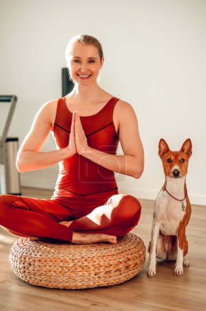 Téléchargez les photos : Belle femme sportive pratiquant le yoga avec chien dans un studio de fitness - en image libre de droit