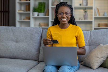 Téléchargez les photos : Femme aux cheveux longs avec ordinateur portable tenant la carte de crédit dans les mains - en image libre de droit