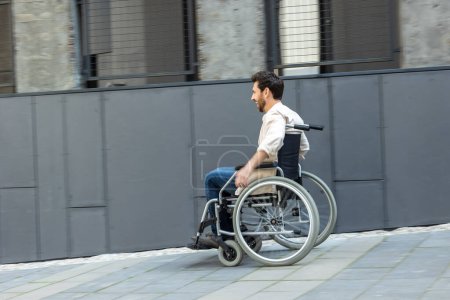 Photo for Man on a wheelchair. Young man riding a wheelchair in a street - Royalty Free Image