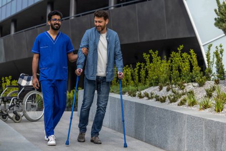 Téléchargez les photos : Marcher ensemble. Homme avec des bâtons marchant avec une infirmière masculine - en image libre de droit