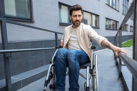 Téléchargez les photos : Handicapés. Jeune homme barbu aux cheveux bruns en fauteuil roulant - en image libre de droit
