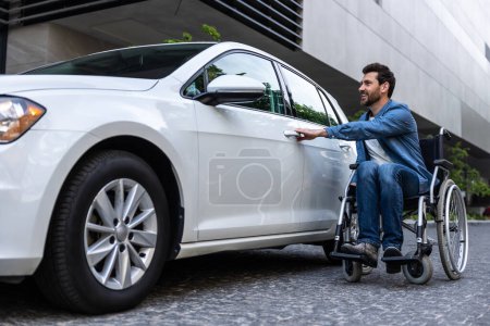 Photo for Disabled man at the car. Bearded disabled man in a wheelchair near the car - Royalty Free Image