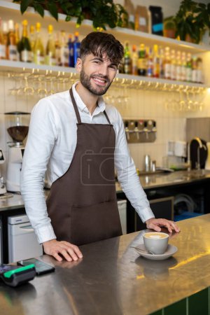 Photo for Caucasian man wearing apron holding coffee cup at cafe creating pleasant environment for customers - Royalty Free Image