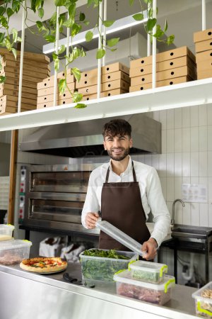 Téléchargez les photos : Homme attrayant travailleur au café cuisine faisant pizza professionnelle - en image libre de droit
