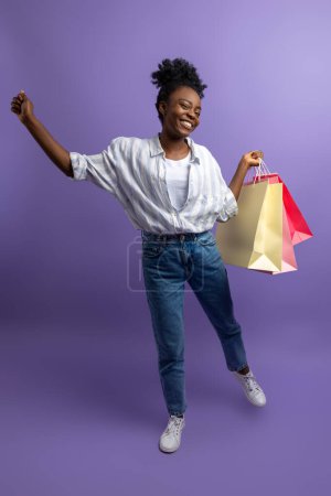 Foto de Después de comprar. Sonriendo bonita chica de piel oscura con bolsas de regalo mirando emocionado - Imagen libre de derechos