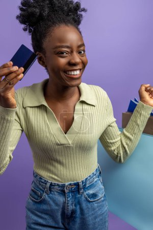 Foto de Amante de compras. Mujer de piel bastante oscura con tarjeta de crédito y bolsas de compras - Imagen libre de derechos