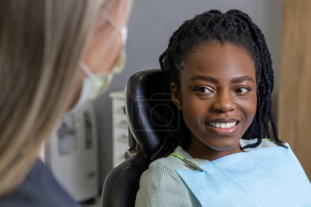 Téléchargez les photos : Dentiste vérifiant les dents de la patiente assise dans un centre médical soins buccodentaires professionnels - en image libre de droit