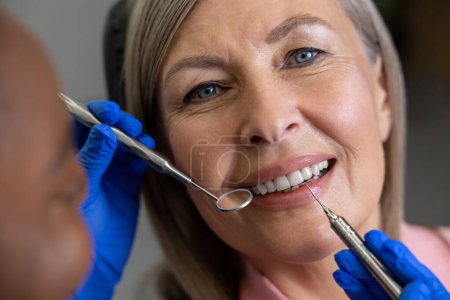 Foto de Mujer que visita la clínica de odontología para el tratamiento dental profesional médico que sostiene la herramienta del instrumento para el examen oral - Imagen libre de derechos