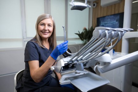Foto de Dentista confiada vistiendo uniforme sentada en la habitación de su médico - Imagen libre de derechos