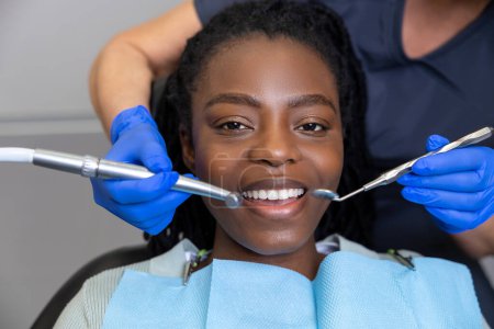 Foto de Dentista mujer examinando paciente con herramientas en clínica dental recibiendo tratamiento dental en clínica - Imagen libre de derechos