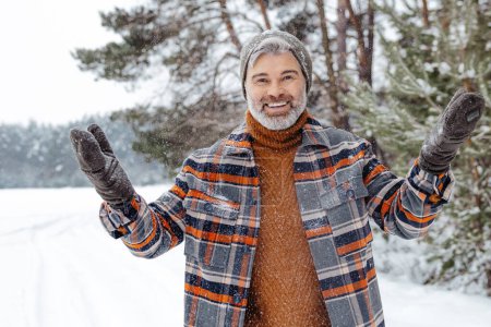 Foto de Me siento emocionado. Hombre con chaqueta a cuadros sintiéndose bien mientras pasa tiempo en un bosque de invierno - Imagen libre de derechos