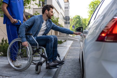 Photo for Opening the door. Dark-haired man on a wheelchair opening a car door - Royalty Free Image