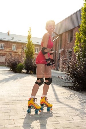 Téléchargez les photos : Jeune femme mignonne sur patins à roulettes regardant apprécié tout en patinant - en image libre de droit