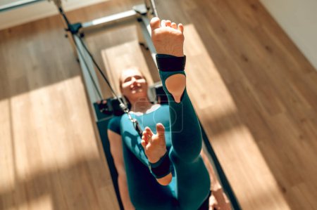 Téléchargez les photos : Femme athlétique à l'entraînement de remise en forme à l'aide de la machine de reformage pour l'entraînement Pilates corps entier - en image libre de droit