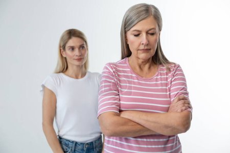 Photo for Conflict. Mom standing with her arms crossed, her daughter behind her - Royalty Free Image