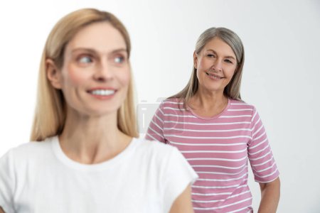 Photo for Mother and daughter. Blonde cute woman smiling nicely, her mom standing behind - Royalty Free Image