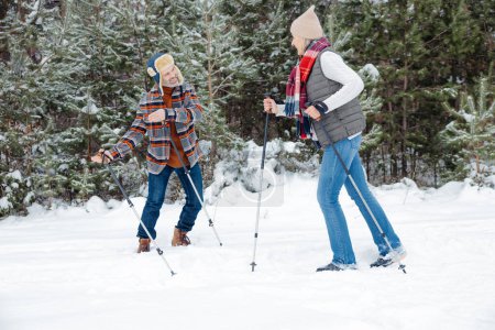 Foto de Actividad invernal. Pareja en un paseo con palos escandinavos - Imagen libre de derechos