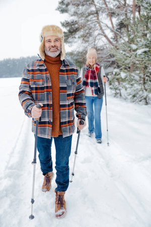 Téléchargez les photos : Activité hivernale. Couple en promenade avec des bâtons scandinaves - en image libre de droit