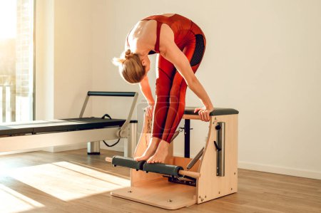 Téléchargez les photos : Attrayant mince femme formation de son corps sportif sur la machine Pilates dans la salle de gym - en image libre de droit