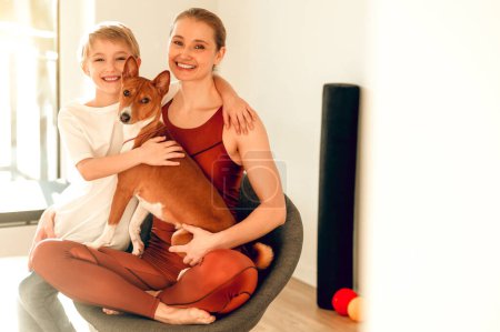Téléchargez les photos : Femme heureuse posant avec son fils et son chien dans un studio de fitness - en image libre de droit