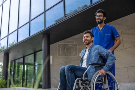Photo for Nurse and patient. Male nurse in a blue doctors overall with a wheelchair - Royalty Free Image
