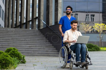 Téléchargez les photos : Je travaille. Homme handicapé assis dans un fauteuil roulant et travaillant sur un ordinateur portable - en image libre de droit