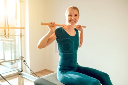Foto de Mujer flexible y delgada haciendo ejercicios de estiramiento en la máquina Pilates en el estudio de yoga - Imagen libre de derechos