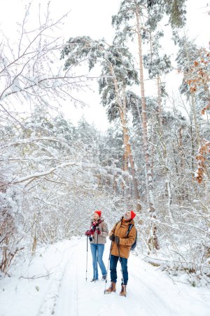 Foto de Buen humor. Hombre y mujer con palos escandinavos en un bosque de invierno buscando disfrutado - Imagen libre de derechos