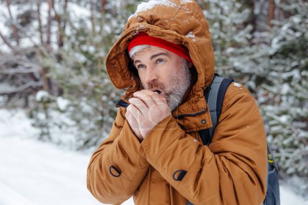 Le froid. Homme en veste chaude se refroidissant dans une forêt d'hiver