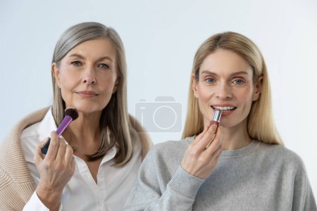 Photo for Beauty tricks. Two beautiful women doing make up and looking contented - Royalty Free Image