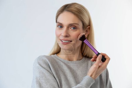 Photo for Make up. Pretty young blonde woman doing make up and smiling - Royalty Free Image