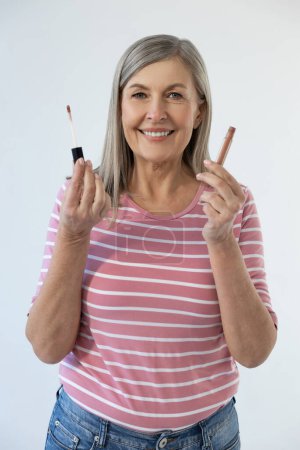 Photo for Lip gloss. Pretty mature long-haired woman using lip gloss and smiling - Royalty Free Image