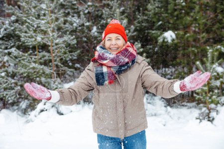 Téléchargez les photos : Météo enneigée. Heureuse femme mûre profitant du temps neigeux dans une forêt - en image libre de droit
