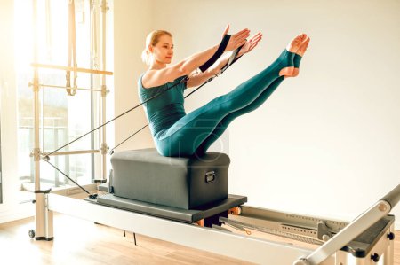 Foto de Mujer tiene sesión de entrenamiento anaeróbico utilizando la máquina de Pilates en el gimnasio para la rutina enfocada y enérgica - Imagen libre de derechos
