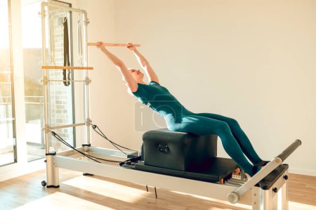 Téléchargez les photos : Femme a séance d'entraînement anaérobie en utilisant la machine Pilates dans la salle de gym pour une routine concentrée et énergique - en image libre de droit