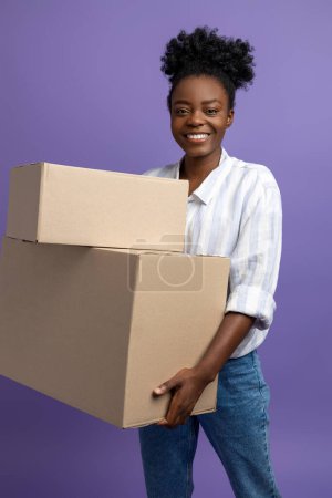 Foto de Chica con cajas. Afro americano rizado chica con cajas sobre un fondo violeta - Imagen libre de derechos