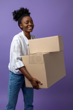 Photo for Girl with boxes. African american curly-haired girl with boxes on a violet background - Royalty Free Image