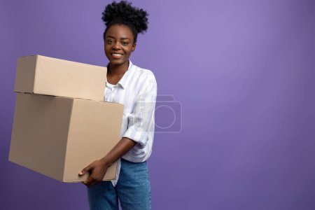 Foto de Centro de embalaje. Sonriente chica de piel oscura con cajas en el estudio - Imagen libre de derechos