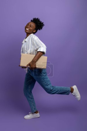 Foto de Centro de embalaje. Sonriente chica de piel oscura con cajas en el estudio - Imagen libre de derechos