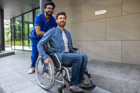 Foto de Discapacitados a pie. Joven enfermero moreno llevando a un paciente en silla de ruedas a caminar - Imagen libre de derechos