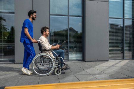 Photo for Rehabilitation center. Tall bearded male nurse carrying the patient on a wheelchair - Royalty Free Image